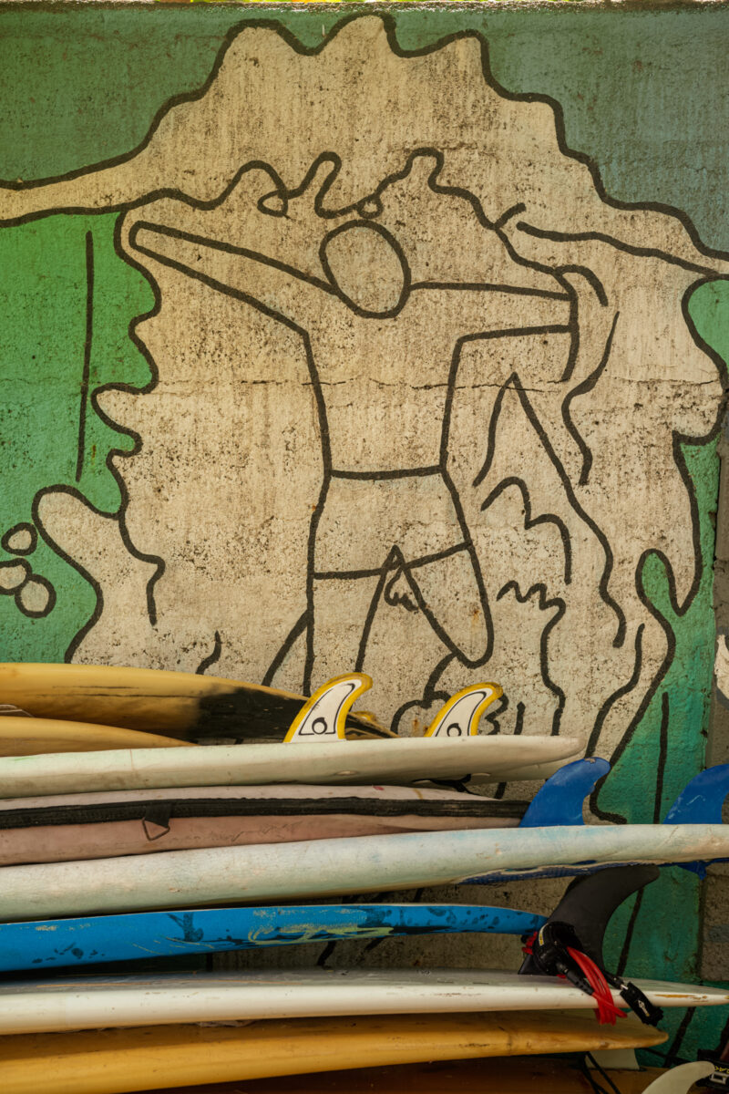 A mural showing a man surfing and a stack of surfboards